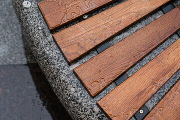 Closeup photo of round bench on the Griboyedov channel embankment in Saint Petersburg on a rainy autumn day in October. Wet wooden planks are laid on a granite pedestal. Overhead view