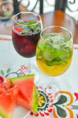 Glasses of red wine and white wine with watermelon pieces on the table. Delicious cold fruit drink served in glasses.