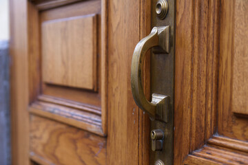 Obraz premium a massive double-leaf wooden door of an old house with a heavy bronze or brass handle