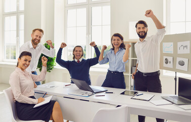 Happy company sales managers celebrating corporate victory during a work meeting