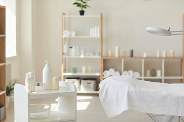 Spa salon room with set of natural skincare products, empty bed and fresh towels