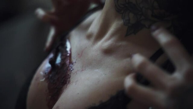 Zombie woman with wounds on her face and chest close-up. Halloween look