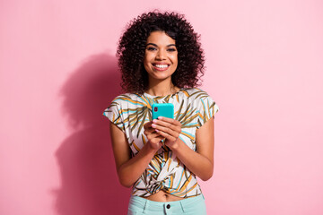 Photo portrait of happy woman holding phone in two hands isolated on pastel pink colored background