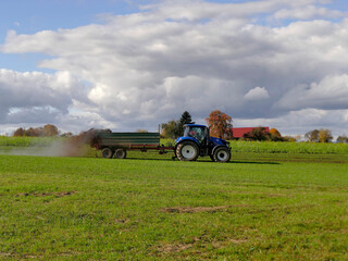 tractor throwing cow manure on a meadow in autumn in Germany