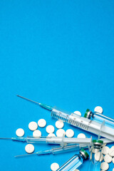 Top view of Pills, Syringe And Ampoule With Vaccination On blue background with copy space