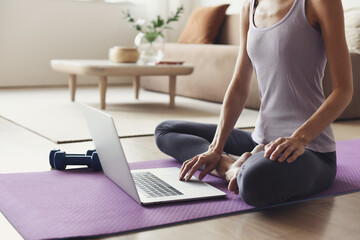 Young woman doing exercises at home, Online video training, Girl using laptop for fitness, Body care, distance exercising, sport, workout, yoga, pilates, healthy lifestyle, online training class.
