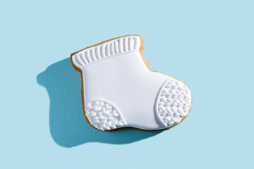 Christmas decorated cookies. New Year tradition. Festive pastry. Winter holiday sweets. Gingerbread biscuit stocking white icing isolated on blue pastel.
