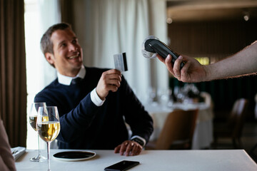 Businessman paying the bill with a credit card in restaurant