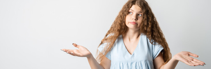 Portrait of confused girl pointing hands in sides. Studio shot, white background. Concept of doubt...