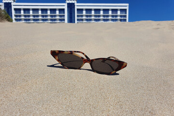 Women's sunglasses on the beach sand. Vacation and tourism concept.