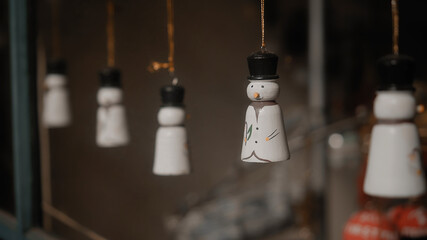 Christmas toys snowmen hang on a thread behind the glass in the house