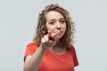 Beautiful blonde girl watching you with suspicious expression. Studio shot, white background....