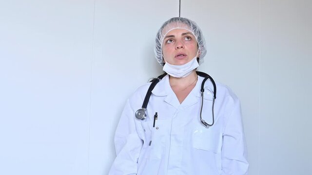 A doctor in a white coat, protective mask and gloves demonstrates powerlessness and fatigue. Medical concept during the COVID 19 coronavirus pandemic. High quality 4k footage