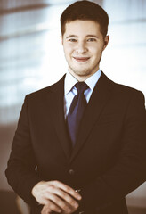 Young businessman wearing suit, with watch, while standing in the office. Business success concept nowadays