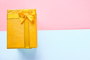 Yellow gift box with bow ribbon on the pink and blue background, birthday, Christmas, Valentine day concept