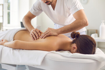 Obraz na płótnie Canvas Woman patient getting back massage procedure from professional chiropractor