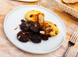 Traditional Spanish blood sausage slices with rice served with baked potatoes..