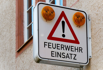 Sign on a facade indicating that the yellow warning lights flash when the fire brigade is on...