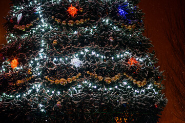 snowfall walk down the street past the dressed up festive Christmas tree and colored figures-multi-colored balls