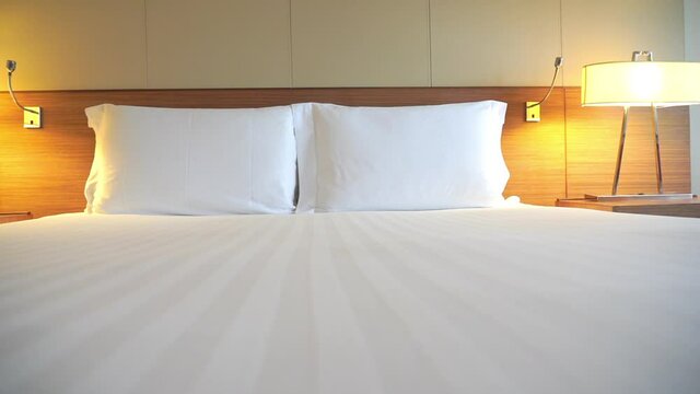 A camera at the foot of a hotel suite bed, pans across the edge.