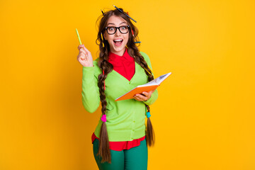 Portrait of attractive excited brainy genius cheerful teenage girl writing essay solution isolated over bright yellow color background