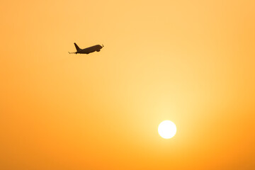 上昇する旅客機と夕日