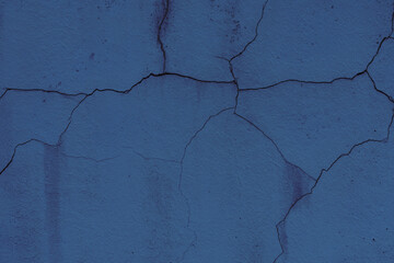 Fototapeta premium Texture of a wall covered with dark blue aged plaster. There are cracks on the surface of plaster