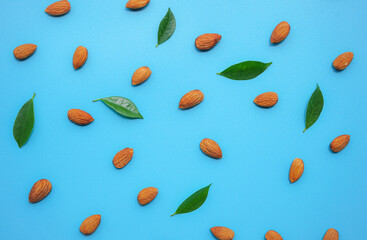 pattern of almonds nuts arrange on blue background with green leaf