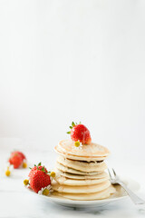 Stack of pancakes with strawberry and maple syrup.