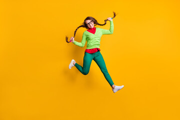 Fototapeta na wymiar Full length body size view of attractive funky girlish cheerful girl jumping running holding pigtails isolated bright yellow color background