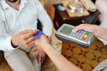 Hands of hotel guest paying for room service with credit card