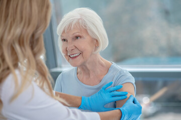 Long-haired female nurse making vaccination to an elderly woman