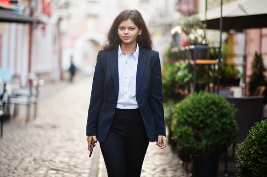 Gorgeous indian woman wear formal posing at street with mobile phone at hands.