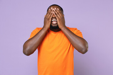Cheerful excited young african american man 20s wearing basic casual orange blank empty t-shirt...