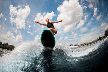 Athletic woman in swimming vest having fun and jumping on the board on the river