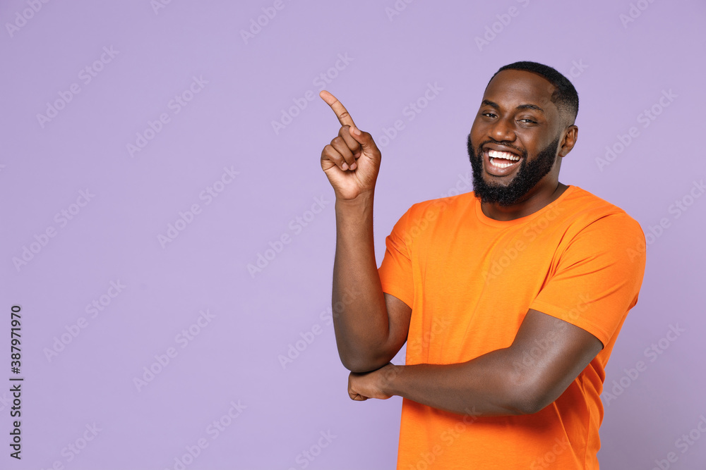 Wall mural smiling cheerful young african american man 20s wearing basic casual orange t-shirt standing pointin