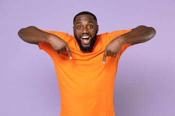 Surprised young african american man 20s wearing basic casual orange t-shirt standing pointing...