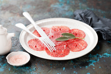 Beef carpaccio. Raw meat sliced on a plate, selective focus.