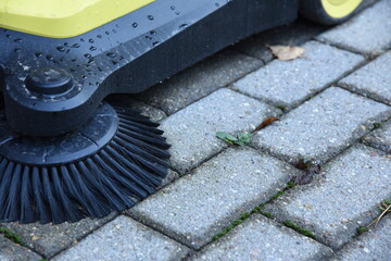 Outdoor pathway cleaning machine in park or garden with brushes. Machinery cleaning pedestrian...