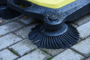 Outdoor pathway cleaning machine in park or garden with brushes. Machinery cleaning pedestrian...