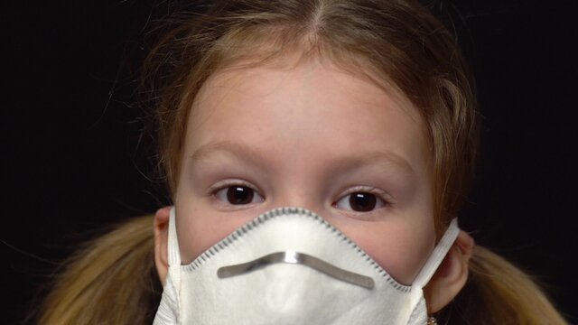 Coronavirus And Air Pollution Concept. Little Girl Wearing Mask For Protect. Wuhan Coronavirus And Epidemic Virus Symptoms. Stares At The Camera. Encourages A Sense Of Guilt In Front Of Children