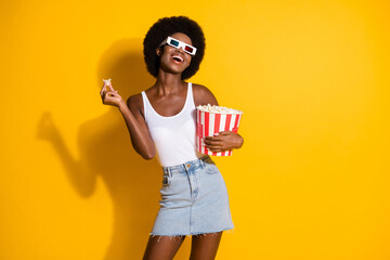 Obraz premium Portrait of attractive slim cheerful wavy-haired girl eating corn having fun free time isolated over bright yellow color background