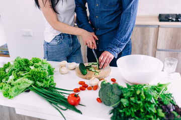 Lovely couple preparing food together, making fresh vegetable sa
