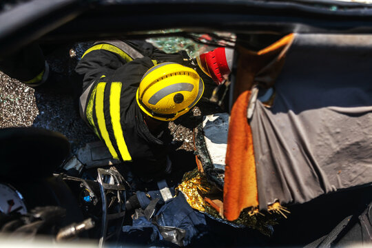 Firemen trying to release man from crashed car. There is a crashed cars in car accident.