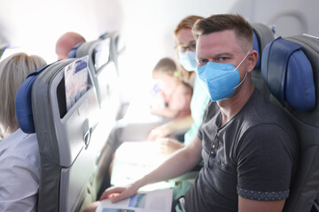 Fototapeta na wymiar Family in medical protective masks are sitting in cabin of plane. Safe travel in coronavirus pandemic concept