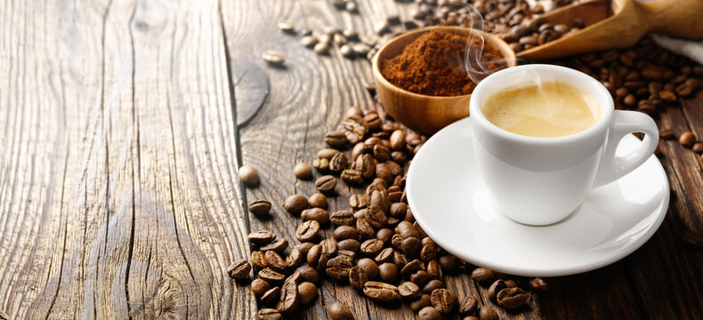 Espresso coffee cup and beans on old wooden table. Wide format