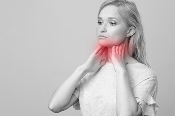 Female checking thyroid gland by herself. Close up of woman in white t- shirt touching neck with red spot. Thyroid disorder includes goiter, hyperthyroid, hypothyroid, tumor or cancer Health care.