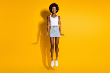 Full length body size view of pretty cheerful wavy-haired girl jumping having fun isolated over shine yellow color background