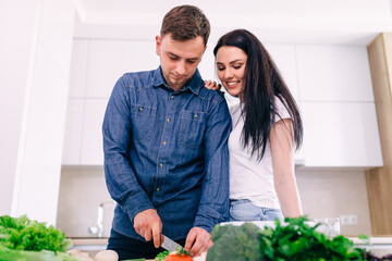 Happy couple preparing delicious lunch in the kitchen. Girl hold