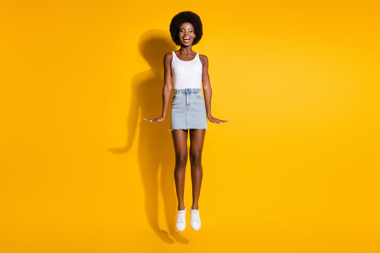 Full length body size view of pretty cheerful wavy-haired girl jumping having fun isolated over shine yellow color background